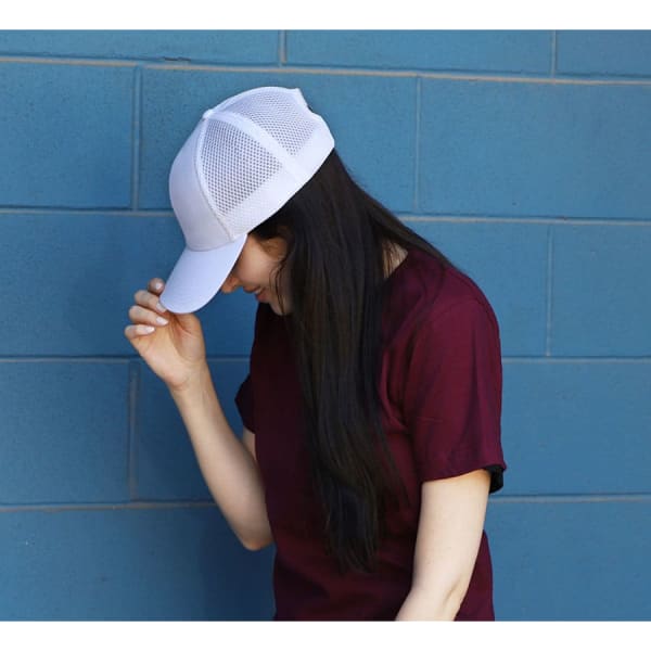 A woman wearing a white polyester/mesh cap against a blue wall, with her head tilted down.