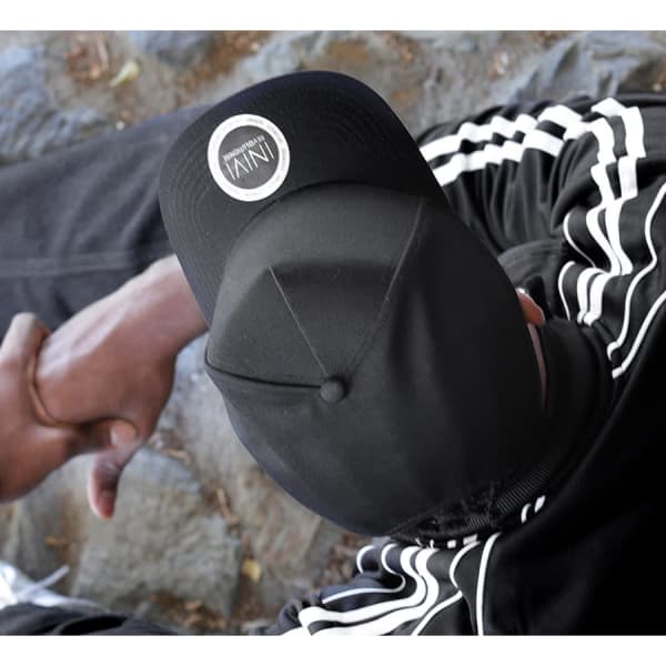 A black cap with a logo, featuring a sleek design, resting on a person’s head.