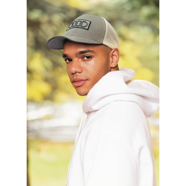 A breathable grey poly twill cap with honeycomb mesh, featured on a model wearing a white hoodie.
