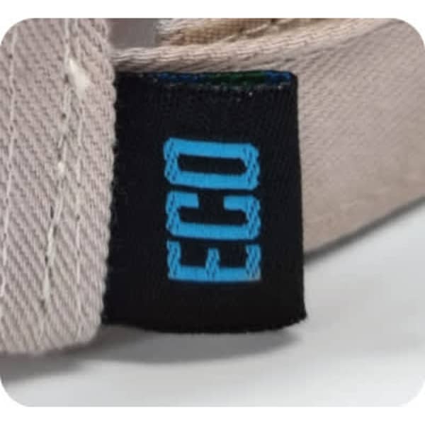 A close-up of a beige cap featuring a small black tag with a blue logo, indicating it is eco-friendly.
