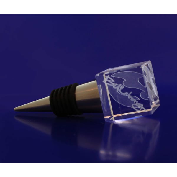 A drink bottle stopper made of clear crystal with a silver metal base, featuring an engraved design.