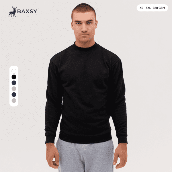 A crew sweatshirt in black, featuring long sleeves and a round neckline. The model is standing against a neutral background.