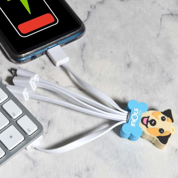 A custom PVC charging cable in white, featuring a cute dog design, positioned next to a smartphone and keyboard.