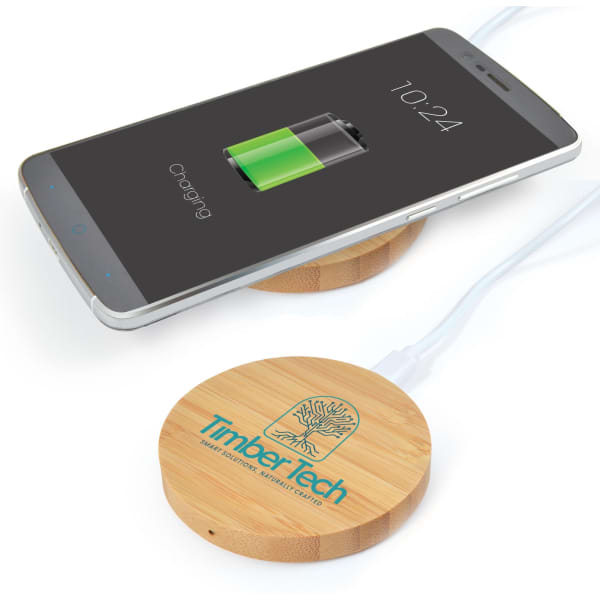 A round bamboo wireless charger in natural wood finish, placed under a smartphone displaying a charging battery icon.