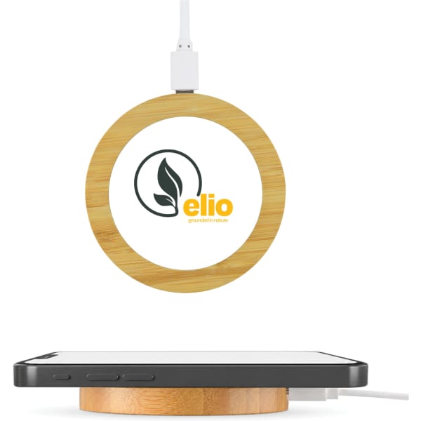 A circular bamboo wireless charger with a logo, positioned above a black smartphone.