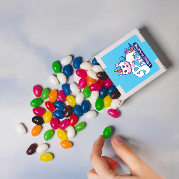 Assorted jelly beans in vibrant colours spilling from a 50g box, with a hand reaching for one.
