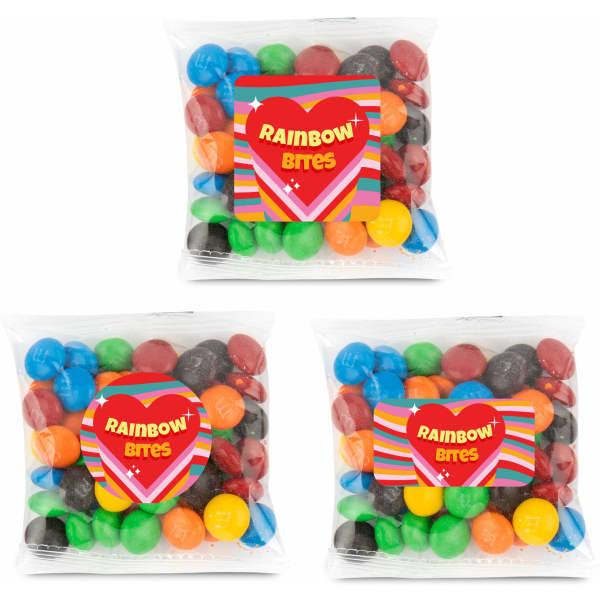 Three clear cello bags filled with colourful chocolate-coated beans in various shades, including blue, red, green, yellow, and black.