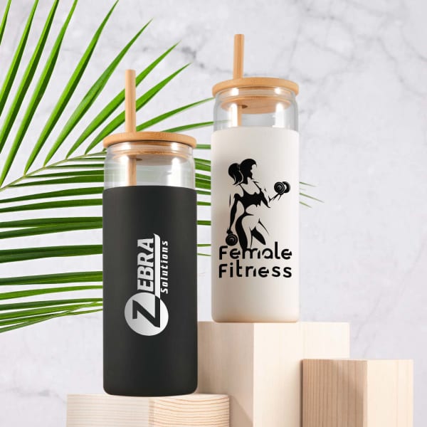 A set of glass tumblers featuring black and white designs with wooden lids and straws, displaying logos and illustrations.