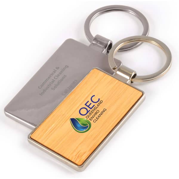 A rectangular bamboo keytag with a silver metal keyring, featuring a logo on the bamboo surface.