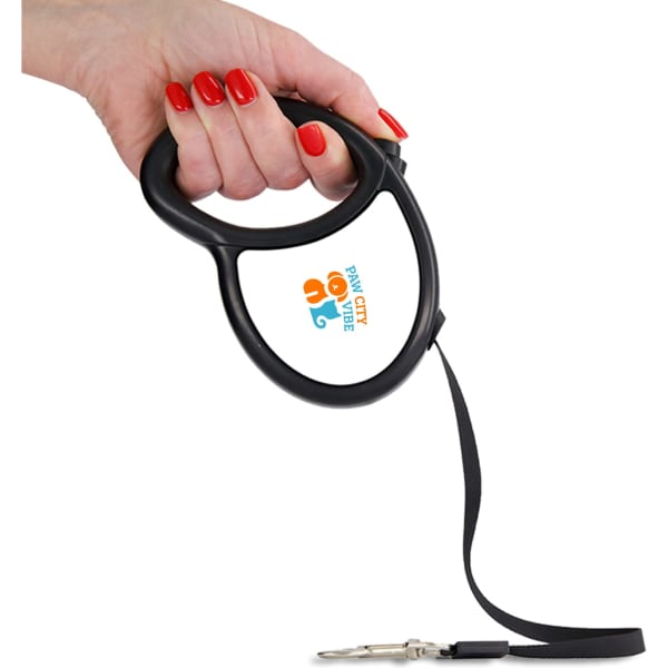 A black retractable dog lead is held by a hand with red nails, featuring a logo on the grip.