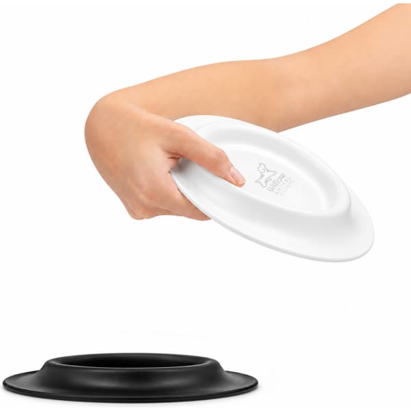 A white and black pet bowl is being held by a hand, featuring a sleek design and a logo on one side.