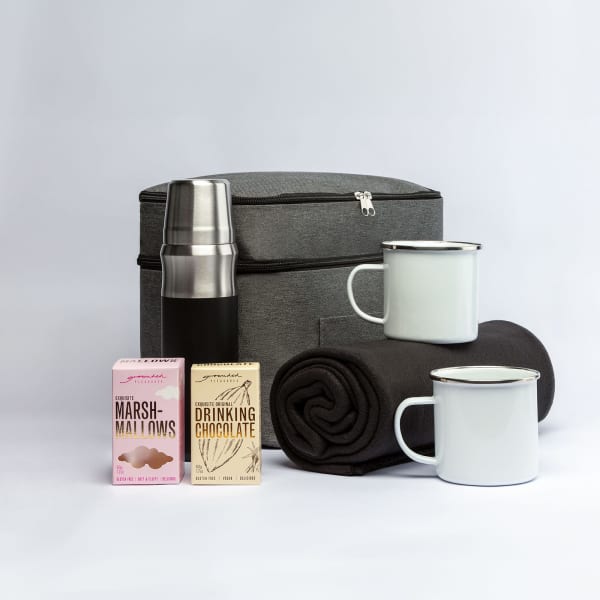 A grey cooler bag with a drink bottle, marshmallows, drinking chocolate, two mugs, and a black blanket.