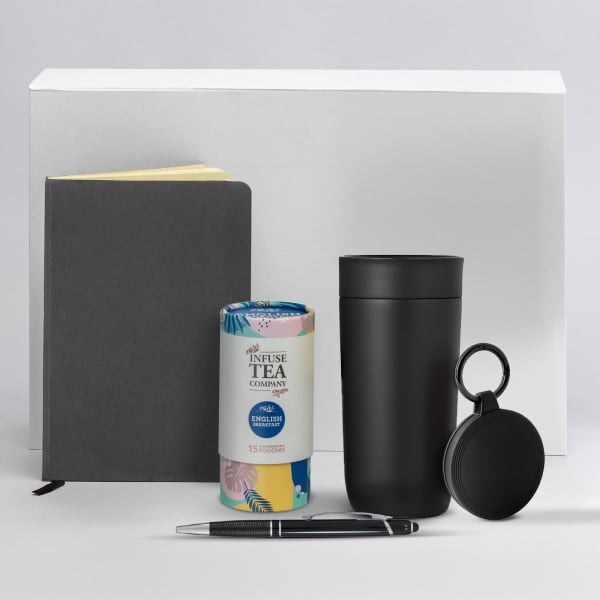 A black drink bottle, a grey notebook, a tea tin with a colourful design, a pen, and a black keychain.