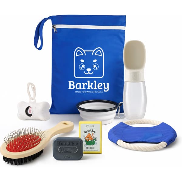A blue bag contains a brush, rope toy, bowl, dog soap, and a drink bottle, all designed for pet care.