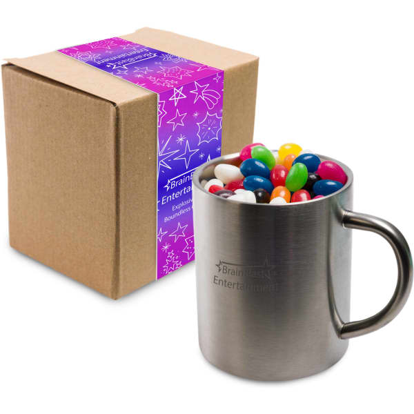 A stainless steel mug filled with assorted colour mini jelly beans, beside a brown cardboard box with a design.