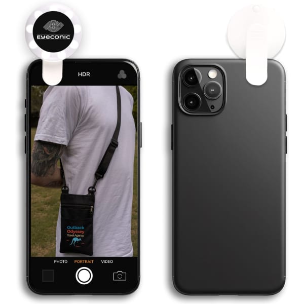 A black smartphone featuring a selfie light attachment, displaying a person wearing a bag in the background.
