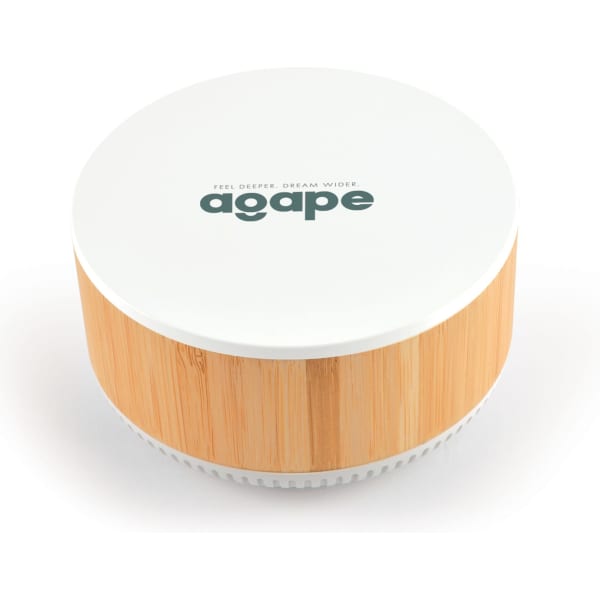 A round speaker and wireless charger in white and bamboo, featuring a logo on the top.