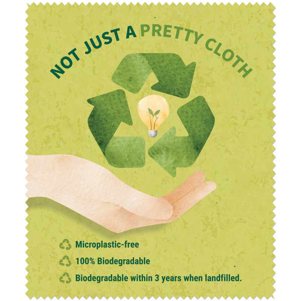 A hand holds a green biodegradable lens cloth featuring a recycling symbol and a light bulb design.