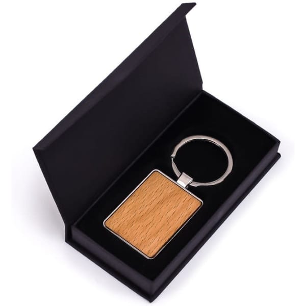 A rectangular wooden keyring in a black presentation box with a silver keyring attachment.