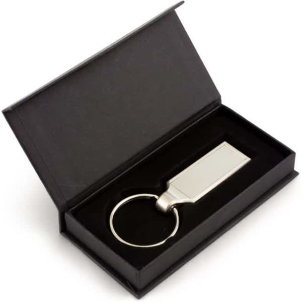 A silver oblong keyring displayed in a black gift box with a sleek interior.