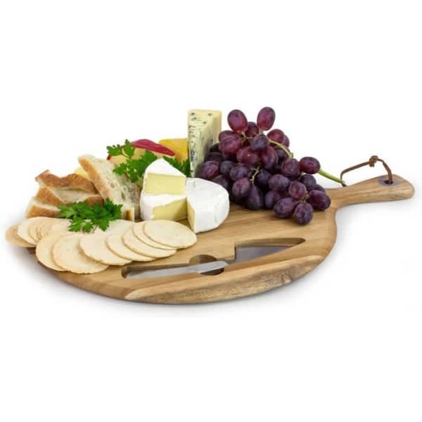 A wooden cheese board featuring assorted cheeses, grapes, bread, herbs, and a knife set.