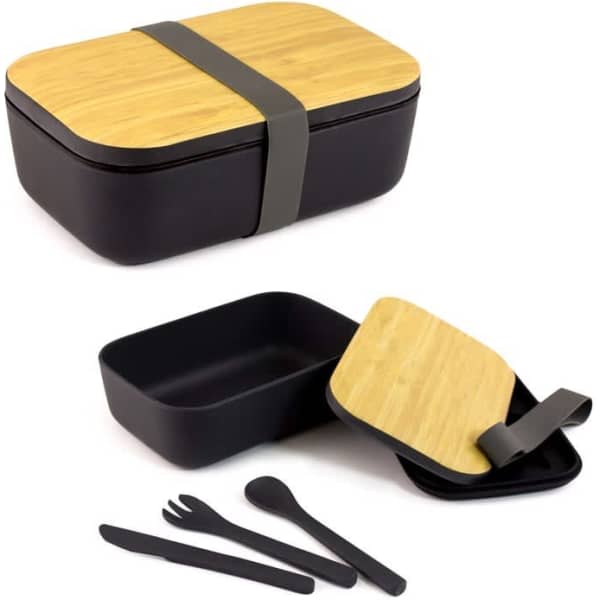 A black bamboo fibre lunch box with a wooden lid, featuring a grey strap and a cutlery set including a fork, knife, and spoon.