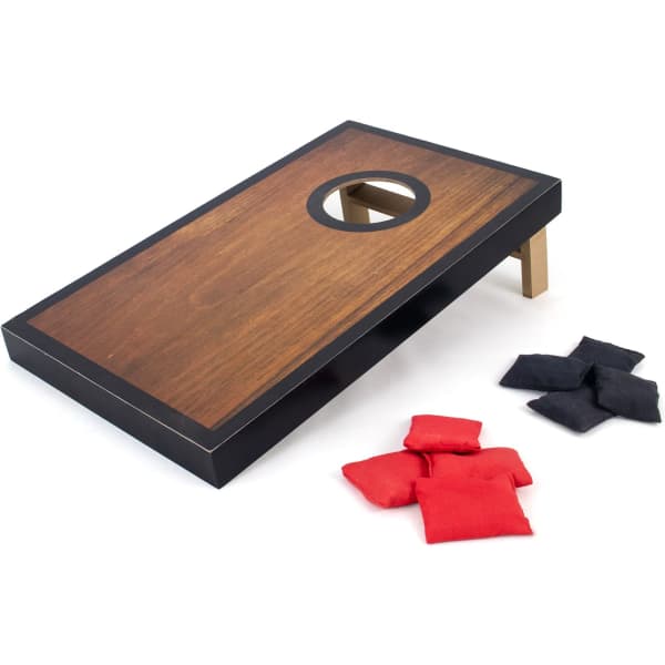 A mini cornhole game set featuring a wooden board with a hole, accompanied by red and black bean bags.