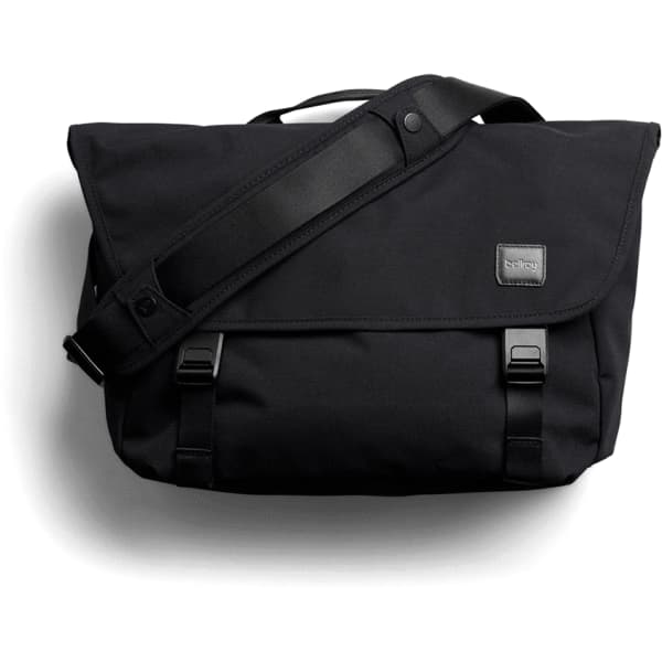A black messenger bag with a flap, adjustable shoulder strap, and branding label. It features buckle closures and a sleek design.