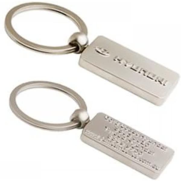 A silver 3D metal key ring featuring a rectangular design with a logo on one side and smooth on the other.