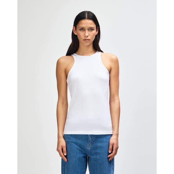 A white women's racerneck tank top with a fitted design, displayed on a model. It features a logo.