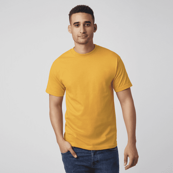 A man wearing a bright yellow unisex heavyweight cotton t-shirt, paired with blue jeans, standing against a plain background.
