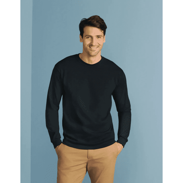 A black long sleeve t-shirt is worn by a smiling man against a light blue background. The shirt features a logo.