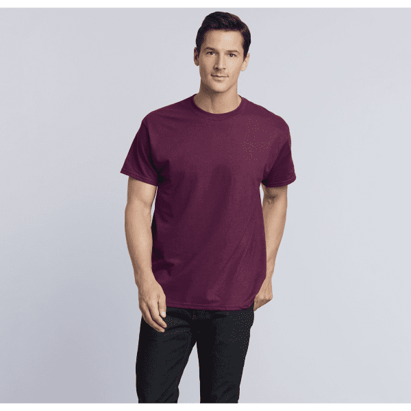 A maroon heavy cotton adult T-shirt displayed on a male model, featuring a simple design and a logo.