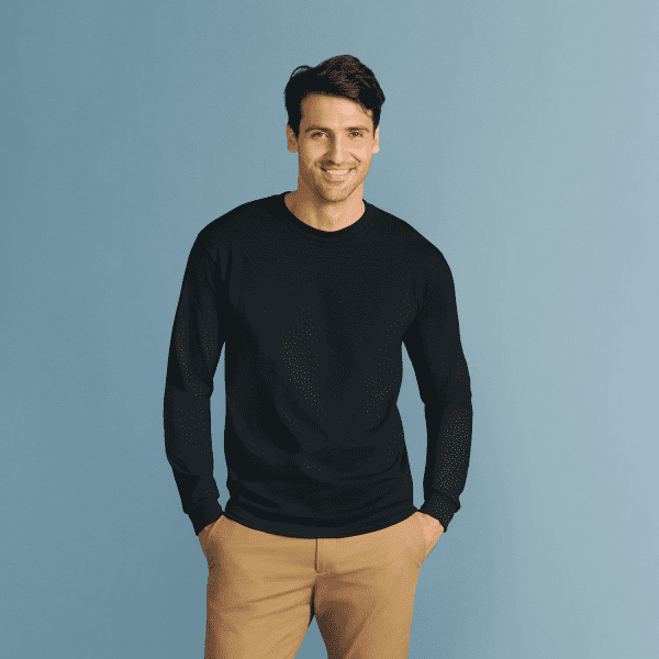 A man wearing a black heavy cotton long sleeve T-shirt, posing with hands in pockets against a blue background.