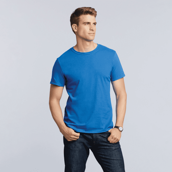 A blue Softstyle adult T-shirt on a model, paired with dark jeans. The shirt has a logo on it.
