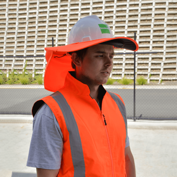 A hard hat with a wide protective brim in white, worn by a person in an orange high-visibility vest.