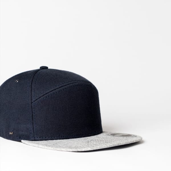 A navy blue six-panel snapback cap with a grey brim, featuring a logo on the side.