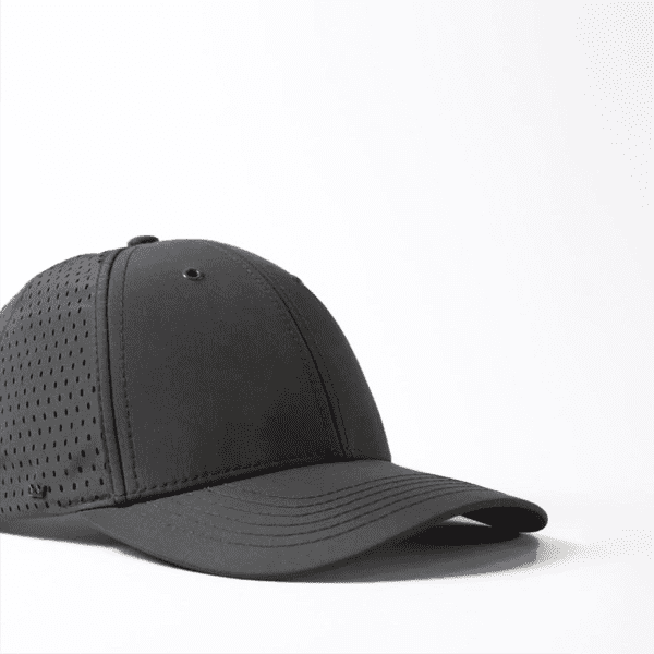 A black snapback cap with a curved peak and perforated design, featuring a logo on the side.