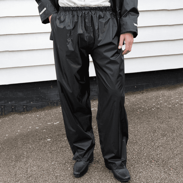 Black adult rain trousers with an elastic waistband, featuring a simple design and paired with black footwear.