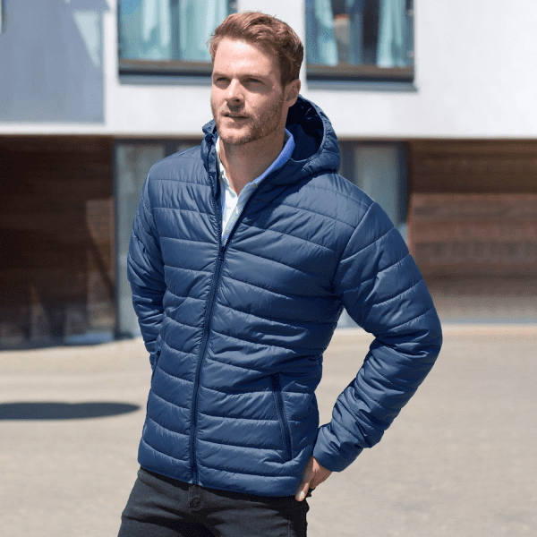 A navy blue soft padded jacket with a hood, featuring a front zip and pockets, worn by a man outdoors.