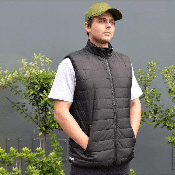A black padded vest worn by a model, featuring a high collar and side pockets, set against a grey background.