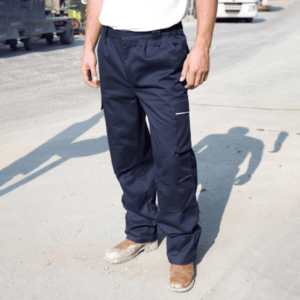 Navy blue action trousers with pockets and a logo, worn by a person standing on a construction site.