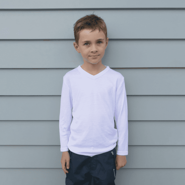 A child wearing a white longsleeve v-neck thermal shirt, standing against a grey background. The shirt has a logo.