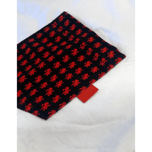 A fabric item featuring a black background with red patterns, displaying a small red tag at the edge.