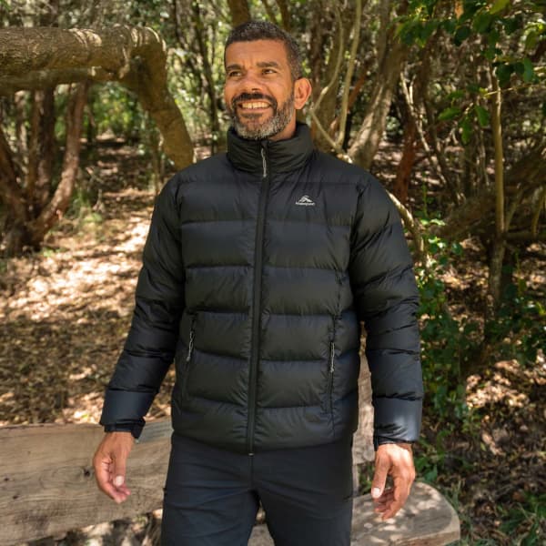 A puffer jacket in black, featuring a high collar and zipped pockets, worn by a smiling man in a natural setting.