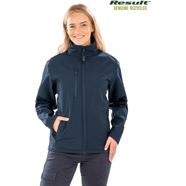 A woman wearing a navy blue softshell jacket with a zip front and side pockets, featuring a logo.