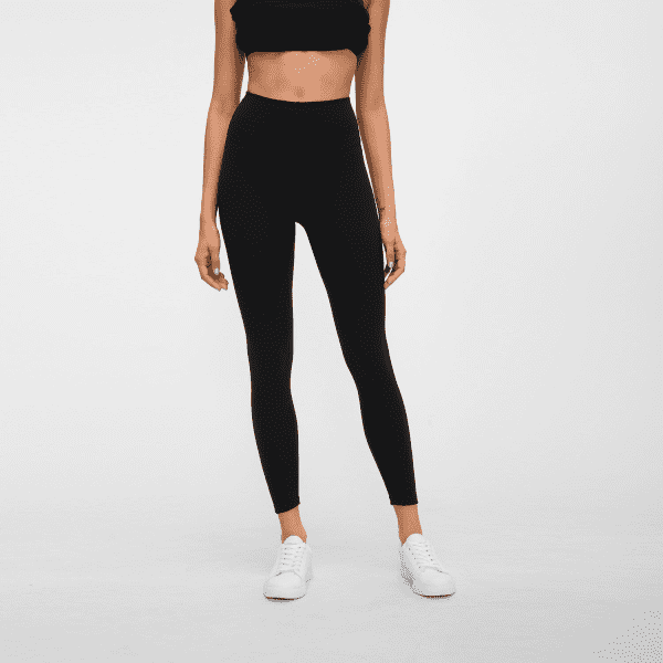 High-rise black leggings featured on a model, paired with a black crop top and white sneakers.