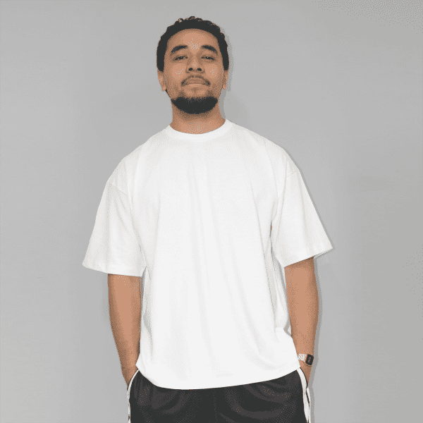 A white oversized T-shirt with short sleeves, featuring a logo on the front. Styled with black shorts.