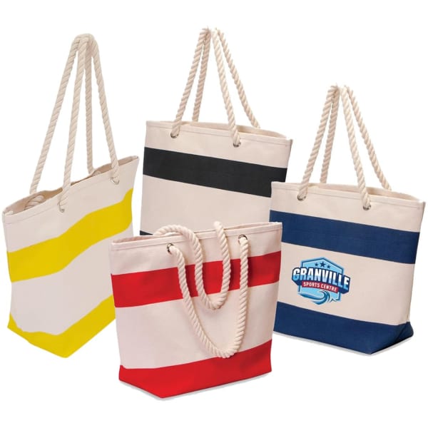 A collection of tote bags in cream, featuring striped designs in yellow, black, red, and navy, with rope handles. One bag has a logo.