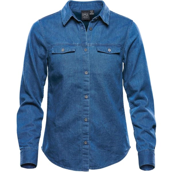 A women's blue denim button-up shirt with long sleeves and two chest pockets. It features a logo.
